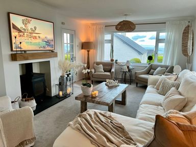 A living room with a white sofa and armchairs around a wooden coffee table at Trem Ynys (3 bed) in Abersoch