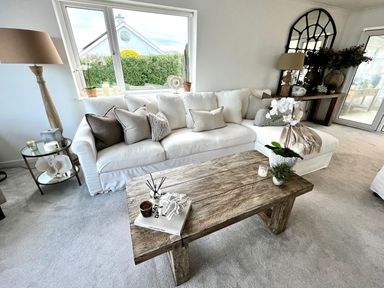 A living room with a white sofa and wooden coffee table with flowers and candles at Trem Ynys in Abersoch