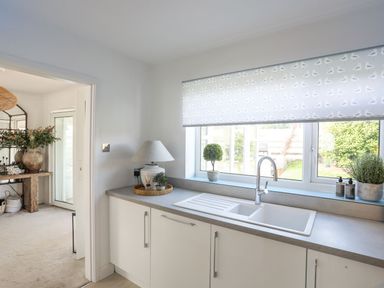 A kitchen sink with a window above it and a lamp on the counter at Trem Ynys 3 bed in Abersoch