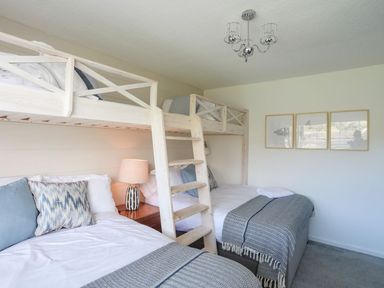 A bedroom with bunk beds pillows a lamp and framed artwork on the wall at Trem Ynys 3 bed in Abersoch