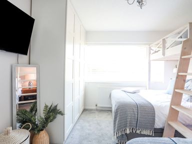 A bedroom with a loft bed wardrobe and a television on the wall at Trem Ynys 3 bed in Abersoch