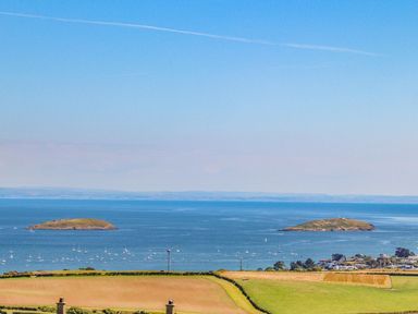 A coastal landscape with fields in the foreground two islands in the water and boats at Trem Ynys (3 bed) in Abersoch