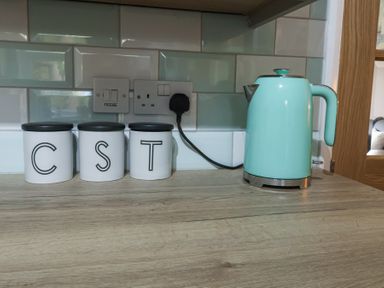 Three white canisters labeled C S T and a mint green electric kettle on a kitchen countertop at 1 Rumsby Cottages Gisleham near Kessingland