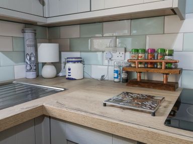A kitchen counter with a sink spice rack jars and a lamp at 1 Rumsby Cottages Gisleham near Kessingland