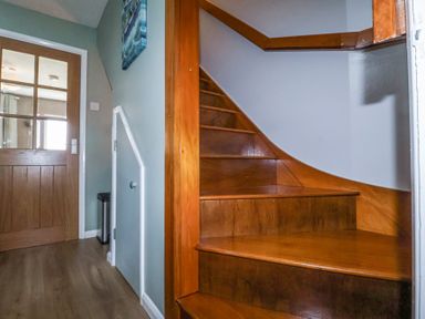 A wooden staircase with a door and a small storage door in a hallway at 1 Rumsby Cottages Gisleham near Kessingland