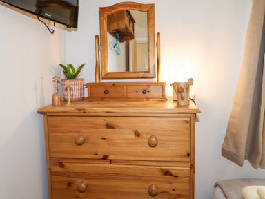A wooden dresser with a mirror on top a plant and decorative items on the surface at 1 Rumsby Cottages Gisleham near Kessingland