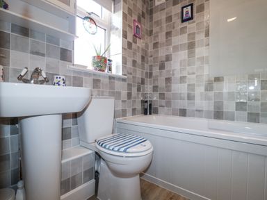 A bathroom with a sink toilet and bathtub with tiled walls at 1 Rumsby Cottages Gisleham near Kessingland