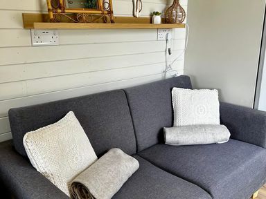 A sofa with cushions and a blanket at Buzzards Lodge near Victoria