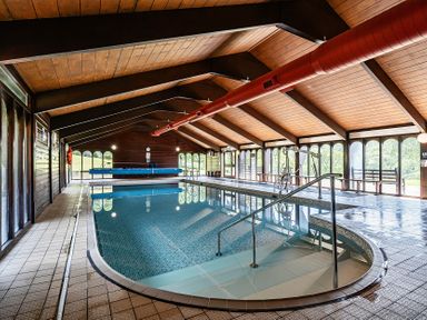 An indoor pool with a railing and seating area at Harcombe House Rooms Accessible Ground Floor Twin in Chudleigh