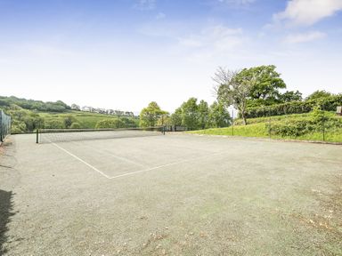 A tennis court with a fence and trees at Harcombe House Rooms - First Floor King in Chudleigh