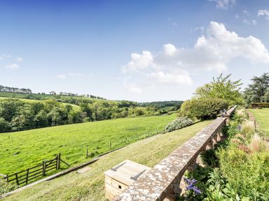 A field with a stone wall and trees at Harcombe House Rooms - First Floor King, Chudleigh