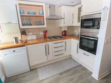 A kitchen with sink, gas stove, oven and dishwasher at Puffin Nook in Broad Haven
