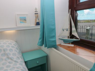 A bedroom with a bed and bedside table at Puffin Nook in Broad Haven