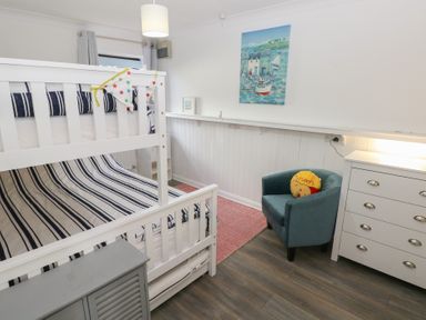A bedroom with a bunk bed and armchair at Puffin Nook in Broad Haven
