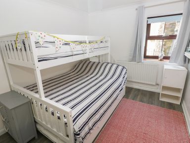 A bedroom with a bunk bed and striped bedding at Puffin Nook in Broad Haven