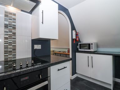 A kitchen with a stovetop oven, cabinets, microwave, and a fire extinguisher at 23 Valley Lodge in Gunnislake