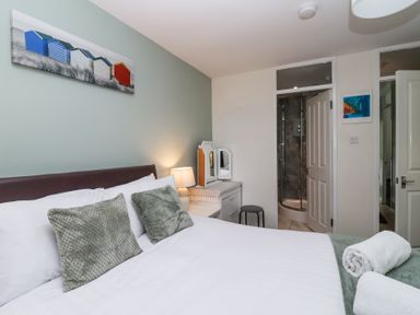 A bedroom with a bed green pillows a lamp a dressing table and an ensuite bathroom at 23 Valley Lodge in Gunnislake
