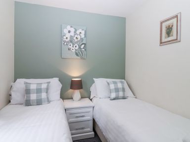 A bedroom with two single beds separated by a white nightstand and a lamp at 23 Valley Lodge in Gunnislake