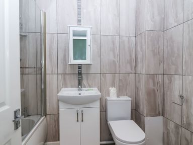 A bathroom with a bathtub shower, sink with vanity cabinet, mirrored cabinet, and toilet at 23 Valley Lodge in Gunnislake