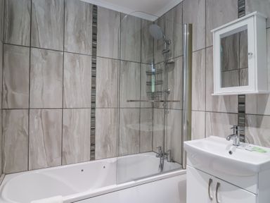 A bathroom with a bathtub shower combination and a sink with a cabinet at 23 Valley Lodge in Gunnislake