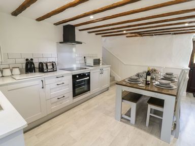 A kitchen with cabinets, oven, and dining area at Cyffdy Cottage - Arenig in Bala