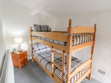 A bedroom with a bunk bed and a nightstand at Cyffdy Cottage - Arenig in Bala