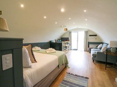 A bedroom with a bed towels a sofa table and chairs and glass doors at Creags in Cullipool Isle Of Luing