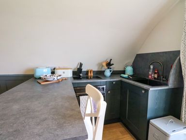 A kitchen with grey countertops a sink a kettle a toaster and kitchen utensils at Creags Cullipool Isle Of Luing