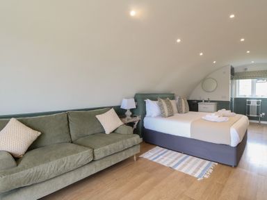A bedroom with a green sofa a bed with pillows folded towels and a small sink at Sula in Cullipool Isle Of Luing