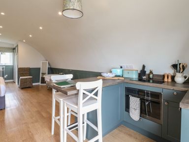 A kitchen area with stools a stove and countertop appliances at Sula Cullipool Isle Of Luing