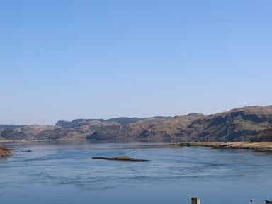 A body of water with hills in the background under a clear sky at Torsa in Cullipool Isle Of Luing