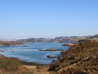 A body of water with small islands surrounded by hills at Torsa in Cullipool Isle Of Luing
