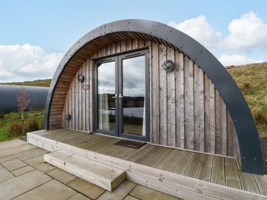 A wooden arched cabin with double glass doors and a small step outside at Fladda in Cullipool Isle Of Luing