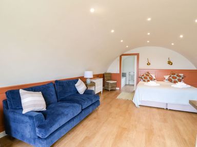 A bedroom with a blue sofa two beds and a small dresser at Losal in Cullipool Isle Of Luing