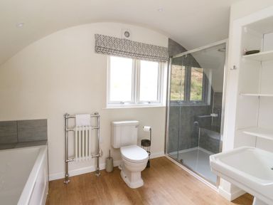 A bathroom with a bathtub radiator toilet glass shower and sink at Losal Cullipool Isle Of Luing