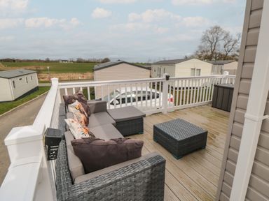 An outdoor deck with a wicker sofa a matching coffee table and a storage box at Meadow View in West Thirston Felton