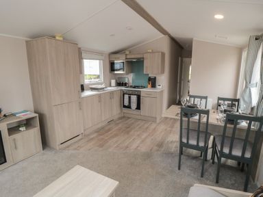 A kitchen with wooden cabinets and a dining table set with plates and glasses at Meadow View in West Thirston Felton