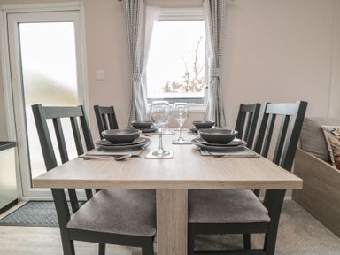 A dining table set with bowls wine glasses and cutlery with six chairs near a window at Meadow View in West Thirston/Felton