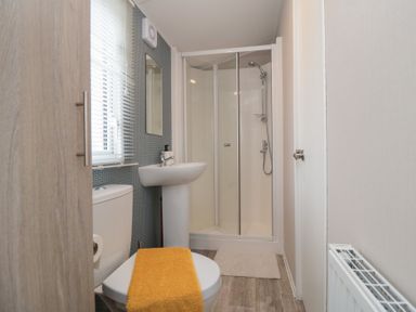 A bathroom with a toilet a sink a shower enclosure and a radiator at Meadow View in West Thirston Felton