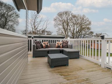 An outdoor deck with a gray wicker sectional sofa and matching table at Meadow View in West Thirston Felton