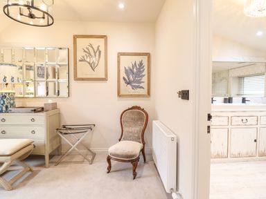 A corner of a room with a chair a dresser a luggage rack and framed prints on the wall at 6 Uppergate Street Rose Cottage in Conwy