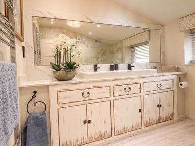 A bathroom vanity with a large mirror a sink towels and a flower pot at 6 Uppergate Street Rose Cottage in Conwy