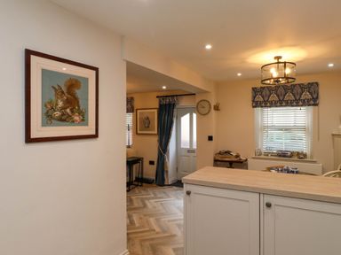 An interior view of a room with a white door blue curtains a wooden floor and framed artwork on the walls at 6 Uppergate Street Rose Cottage in Conwy