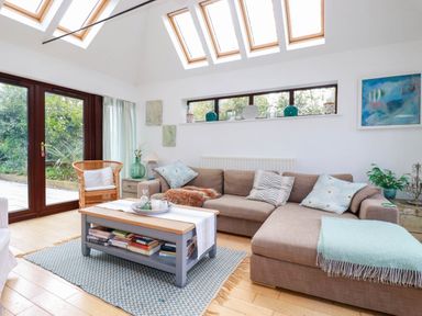 A living room with a large sofa coffee table and skylights at Goatsland in Trebetherick