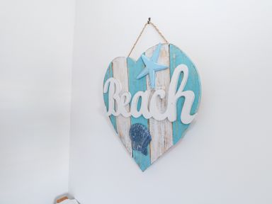 A wall decoration with the word Beach a starfish and a seashell on striped wood at Shrimp Cottage Brewers Quay Harbour