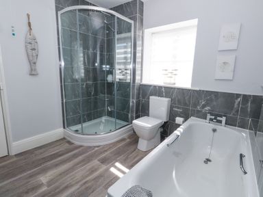 A bathroom with a corner shower, a toilet, a bathtub, and decorative wall tiles at Shrimp Cottage Brewers Quay Harbour