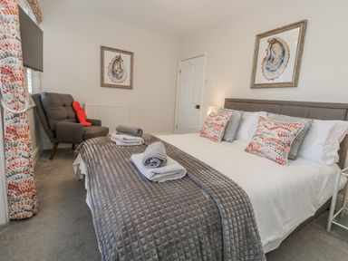 A bedroom with a bed and armchair at Shrimp Cottage in Brewers Quay Harbour