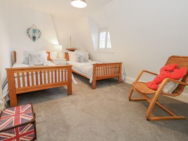 A bedroom with two single beds and a rocking chair at Shrimp Cottage in Brewers Quay Harbour