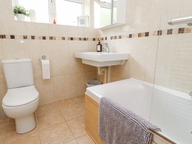 A bathroom with a toilet, sink, bathtub, and towel at 3 Glyn Y Mor in Llanbedrog