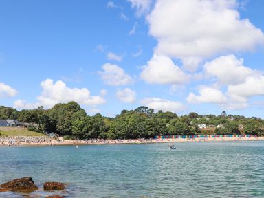 A beach with huts and people at 3 Glyn Y Mor Llanbedrog
